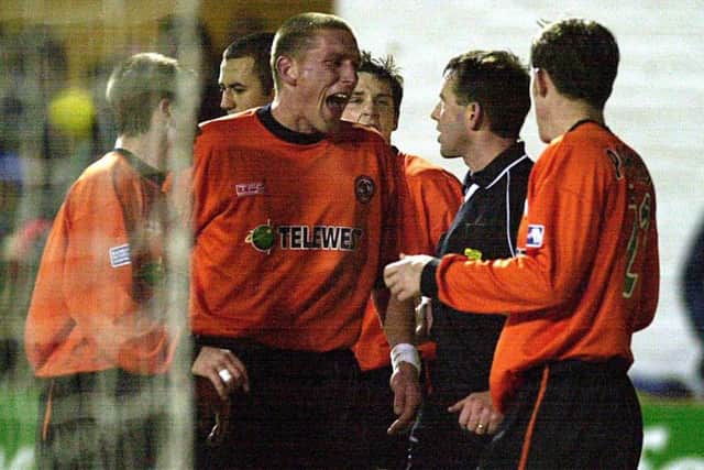 Alan Freeland is surrounded by members  of the Dundee Utd team after awarding Hibs a late penalty