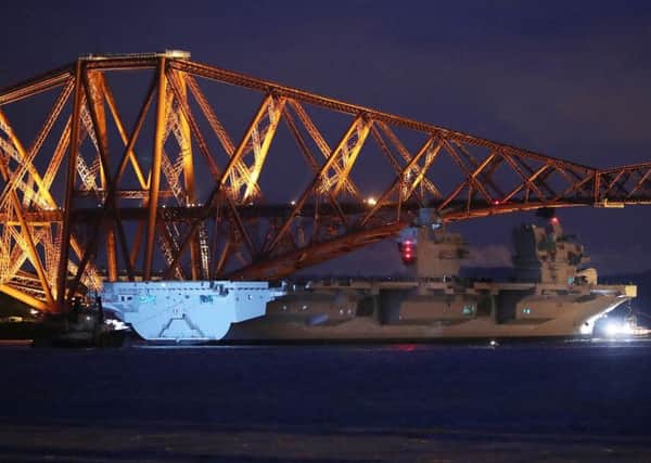 HMS Queen Elizabeth, one of two new aircraft carriers for the Royal Navy, is pulled by tugs under the Forth Rail Bridge in the Firth of Forth, as she sets sail to begin her sea trials.