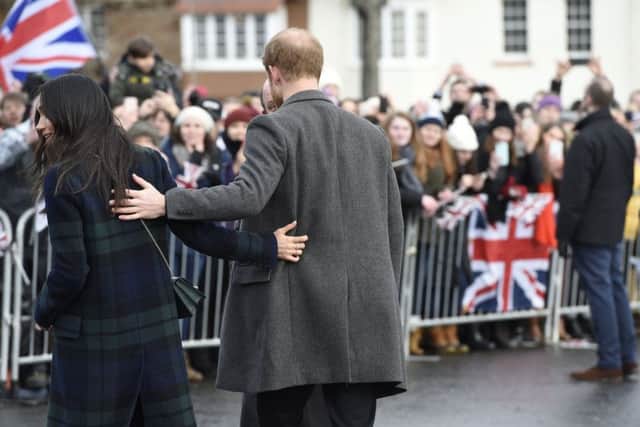 Meghan Markle and Prince Harry reach out for one another while on a  walkabout on the esplanade at Edinburgh Castle, Picture: Ian Rutherford/PA Wire