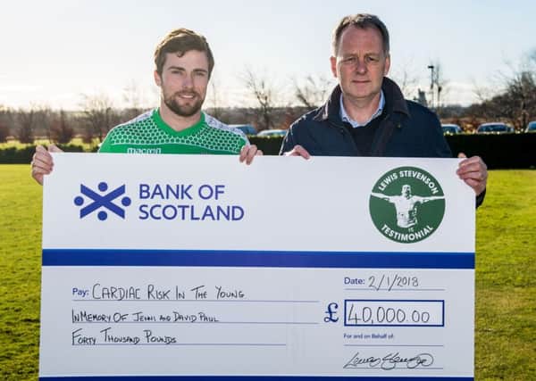 Lewis Stevenson hands the Â£40,000 cheque to Gordon Paul, father of teenage Hibs starlet David, whose death was marked by the team