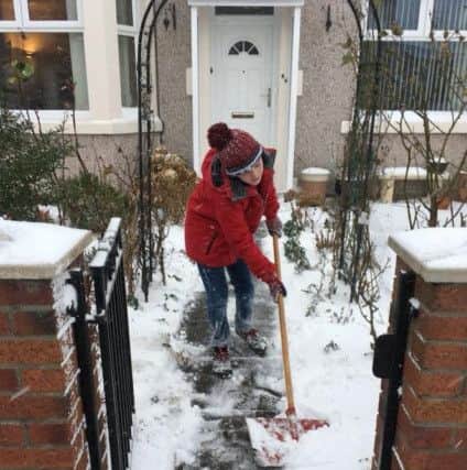A youngster clears snow from a neighbour's path