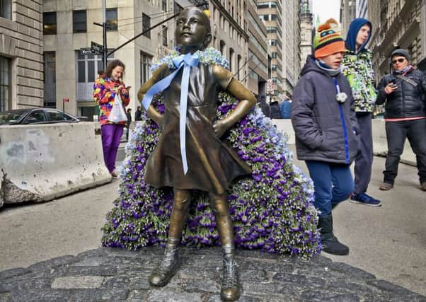 Wall Street's Fearless Girl statue is draped with a bouquet of flowers to mark International Women's Day. Picture:: AP