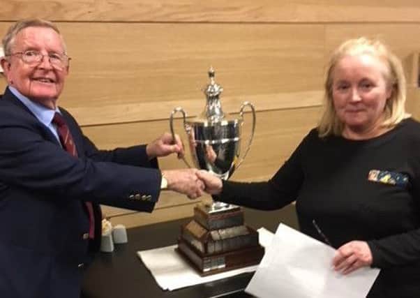 East life member and past president John Anderson receives the UniRoyal Trophy from Margaret Carrell, secretary of West Alliance