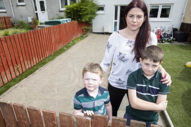 Sue Scorer with her boys Aaron and Charlie in the front garden of their home in Livingston where thieves stole the astroturf.  Picture; SWNS