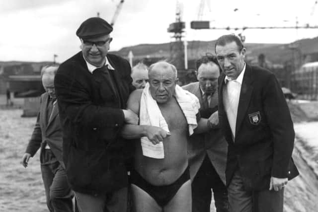 Ned Barnie is helped along Burntisland Harbour to the boat after swimming across the Firth of Forth in 1959. Picture: TSPL