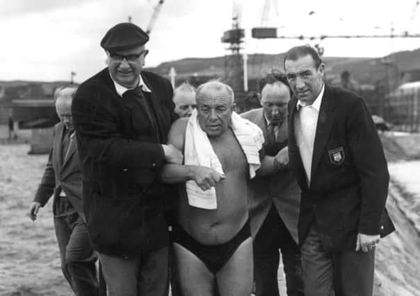 Ned Barnie is helped along Burntisland Harbour to the boat after swimming across the Firth of Forth in 1959. Picture: TSPL