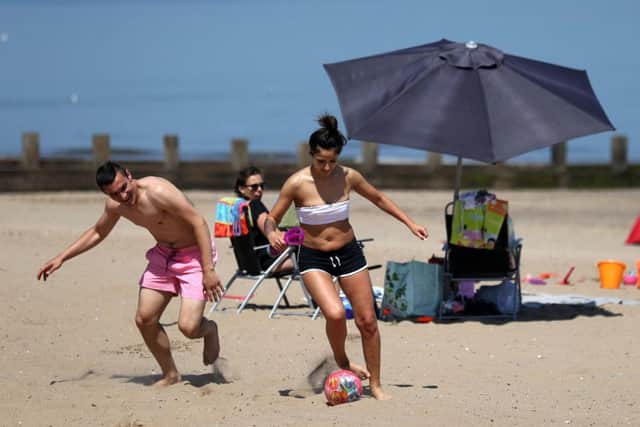 A couple play football on Portobello beach as they take advantage of the hot weather sweeping across the country. Picture; PA