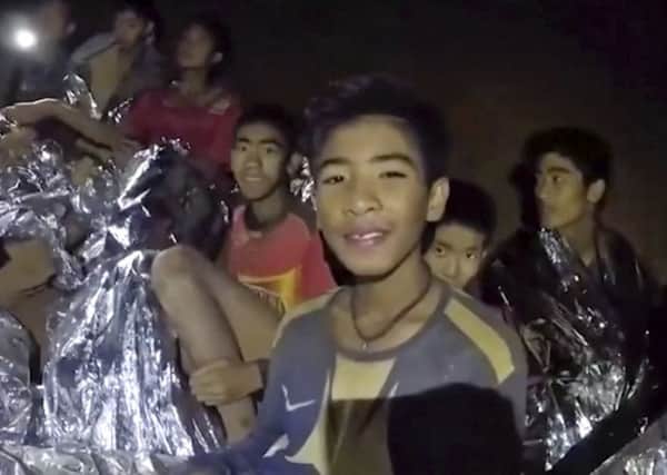 Some of the boys smile as Thai Navy Seals offer help to them inside the cave  (Royal Thai Navy Facebook Page via AP, File)