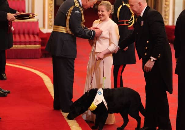 Lora Fachie, with her guide dog Tai, is made an MBE (Member of the Order of the British Empire) by the Prince of Wales at Buckingham Palace. Picture: Yui Mok/PA Wire