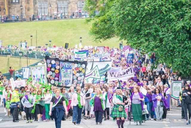 Protesters march in Suffragette colours in Edinburgh to mark the anniversary of women getting the vote in the UK