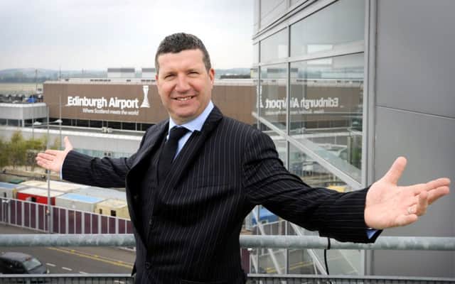 Gordon Dewar, chief executive of Edinburgh Airport, stands alongside the airport's new signage and logo.