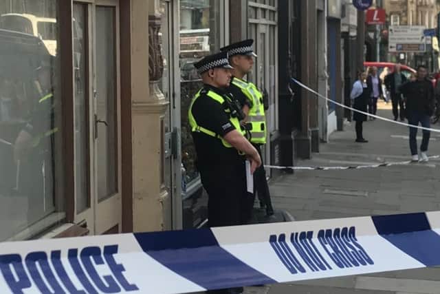 Officers stand guard outside a shop on Home Street