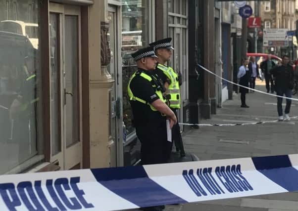 Officers stand guard outside a shop on Home Street