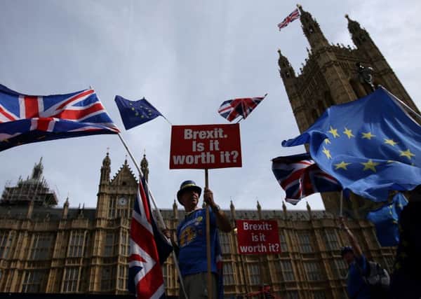 A demonstrator holds a sign that reads "Brexit. Is it worth it?" whilst draped in EU and Union flags as he protests outside the Houses of Parliament. Picture: Getty