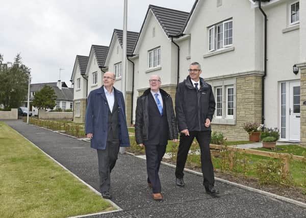 Melville Housing vice-chairman David Bond and Andrew Noble escort Kevin Stewart, Minister for Local Government, Housing and Planning around the development.
