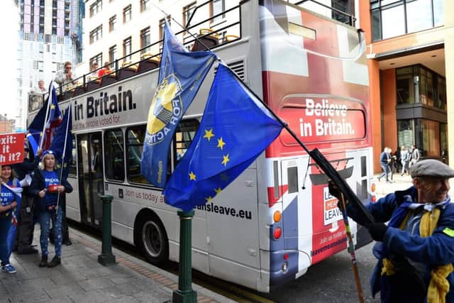 Anti-Brexit protestors carry EU flags as they stand alongside the Leave Means Leave battle bus parked outside a Tory conference fringe event. Picture: Getty