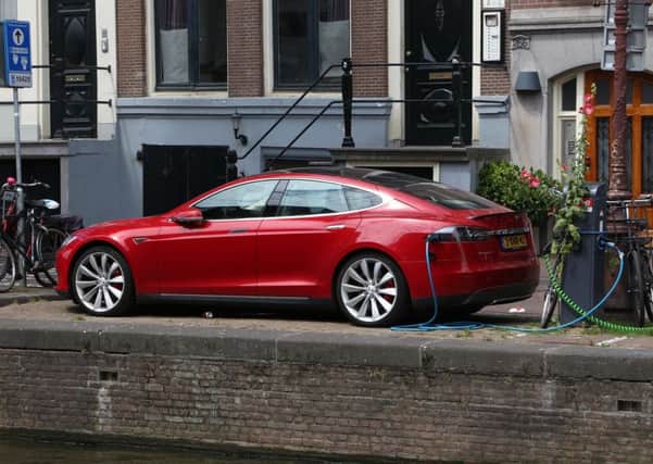 An electric Tesla Model S car charges by the canal in Amsterdam.