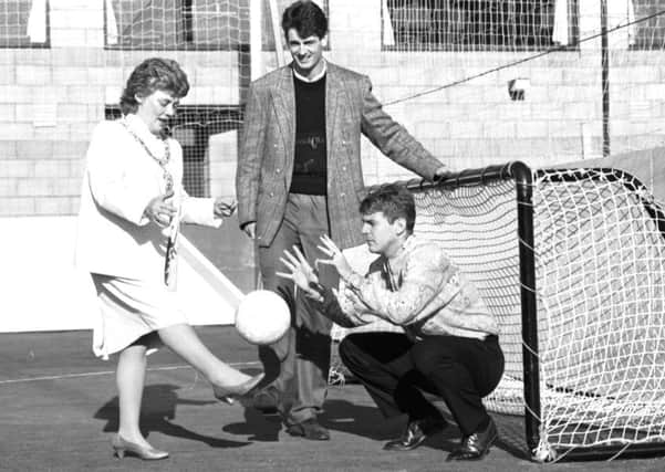 Hearts Dave McPherson looks on as Edinburgh Lord Provost Eleanor McLaughlin kicks the ball to Hibs goalkeeper Andy Goram at the opening of the Pitz in October 1989