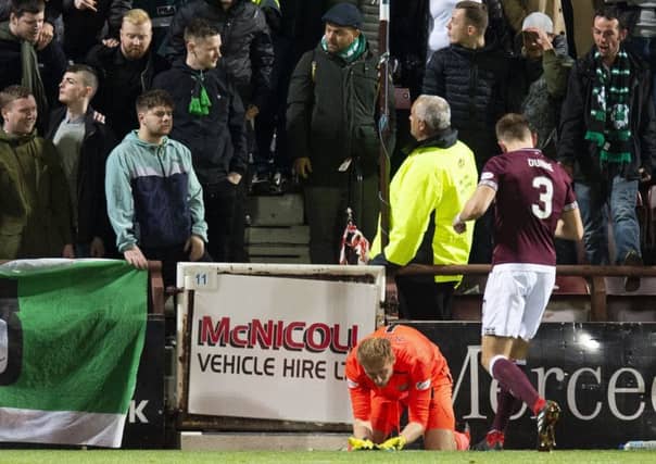 Hearts goalkeeper Zdnek Zlamal lies on the ground after an altercation with a Hibernian fan