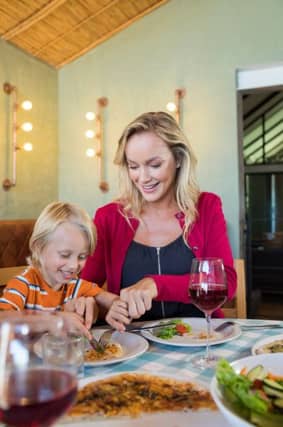Mother assisting son in having food at restaurant