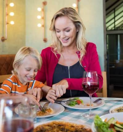 Mother assisting son in having food at restaurant