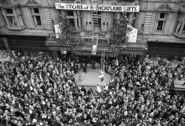 Shoppers outside Patrick Thomson's department store as Santa Claus climbs down a golden ladder.
