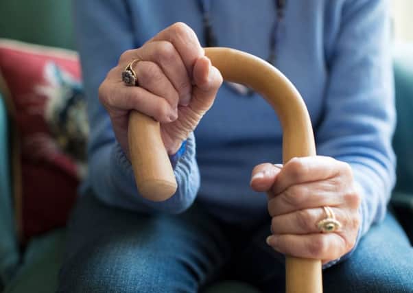 Close Up Of Senior Woman Sitting In Chair Holding Walking Cane