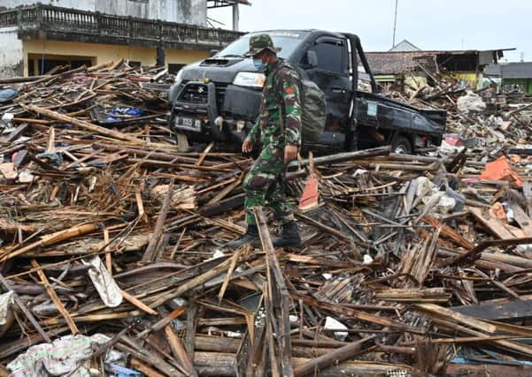 An Indonesian soldier searches for bodies in the debris in Sumber Jaya village in Banten province. Picture: Adek/Getty Images