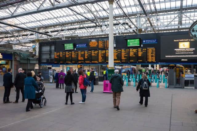 Edinburgh Waverley railway station. People are moving through the turnstiles. Pic: DavidGraham86/Shutterstock