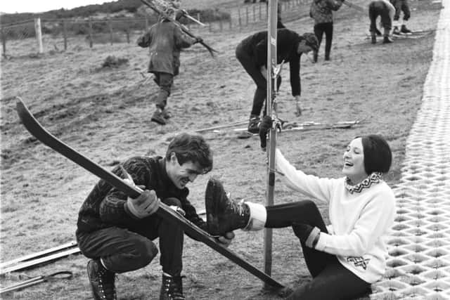 Skiers at Hillend Park when Edinburgh Corporation's artificial ski-slope opened in rainy conditions. Bill Pickering assists Morag Forsyth with her skis.