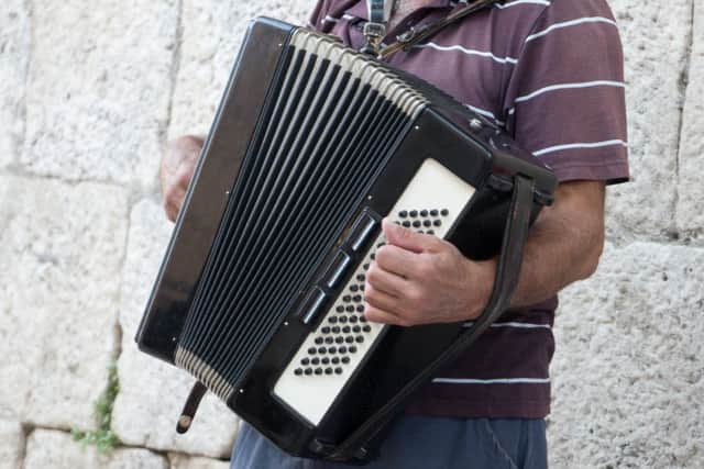 Elderly retired grandfather playing on accordion on the street.