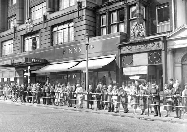 Traffic lights system  at West End  Edinburgh  - People watch new system from barrier in Princes Street.  Shops in the background are Binns and Alex Ferguson.