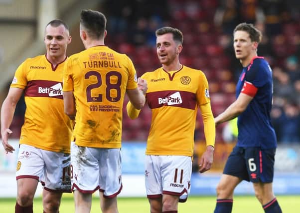 A dejected Hearts captain Christophe Berra looks on as Motherwell celebrate Sunday's last-gasp win. Pic: SNS
