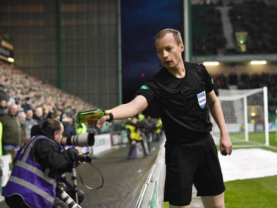 Referee Willie Collum removes a bottle of Buckfast that was thrown on to the pitch during Hibs' Scottish Cup tie with Celtic. Pic: SNS