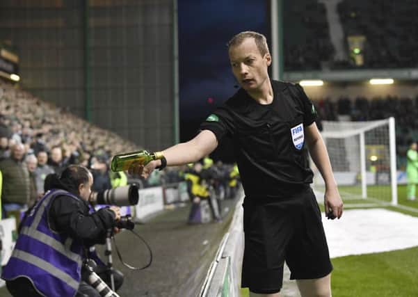 Referee Willie Collum hands over a bottle of 
Buckfast to the police after it was thrown on to the pitch during Hibs 2-0 defeat by Celtic at Easter Road. Pic: SNS