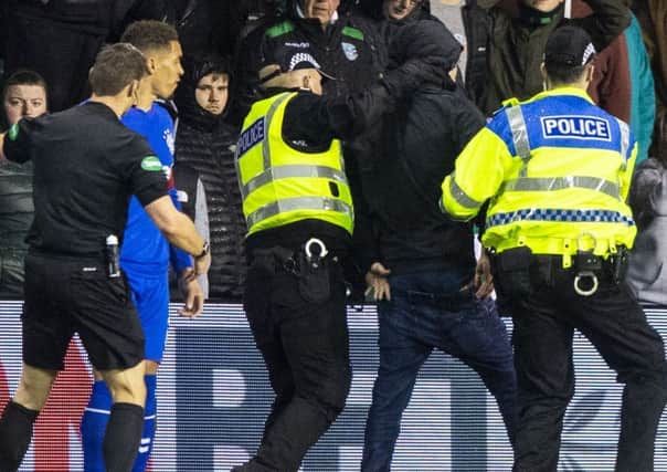 The fan is led away by police after confronting Rangers captain James Tavernier