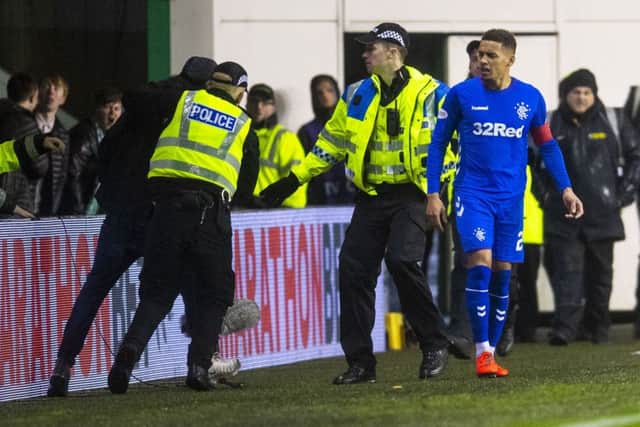 Rangers captain James Tavernier is confronted by a fan who runs onto the pitch