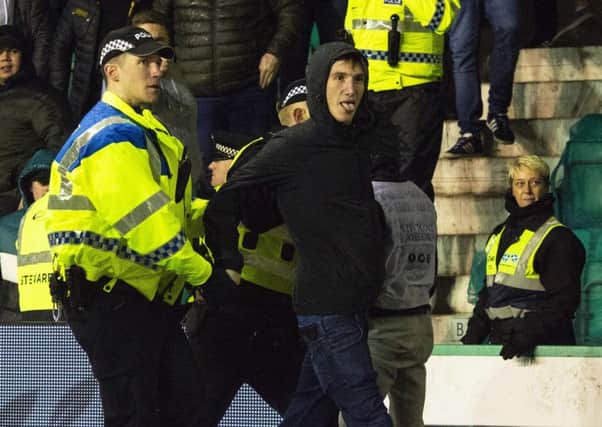 Cameron Mack is led away from Police after running onto the park and confronting James Tavernier