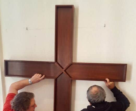 The cross was lifted into place above a stairwell which leads to the sanctuary.