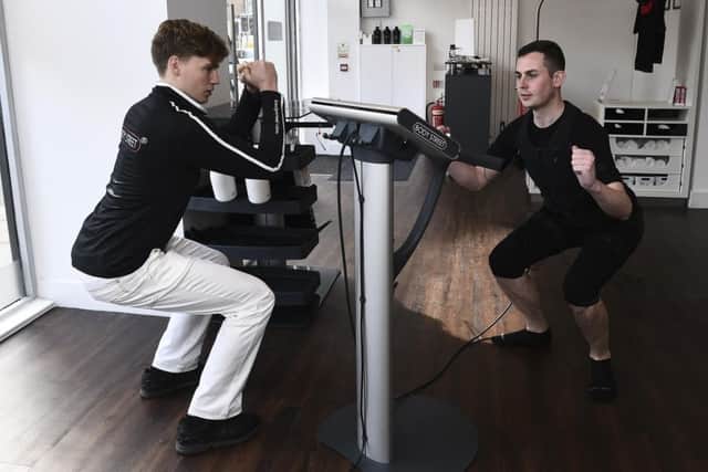 Personal trainer Jason Bertschinger goes through the workout with Kieran