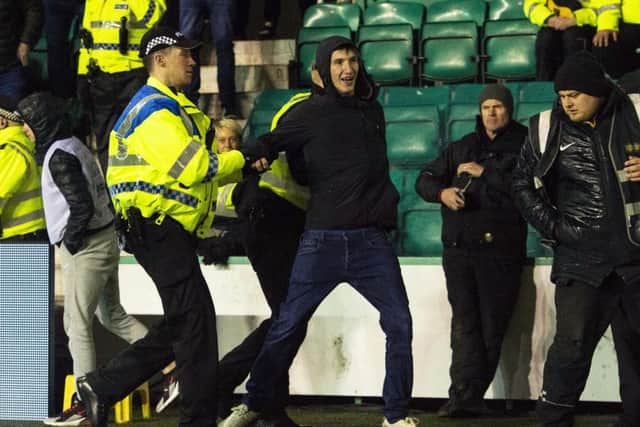 Hibs fan Cameron Mack is led away from Police after running onto the park and confronting Rangers captain James Tavernier
