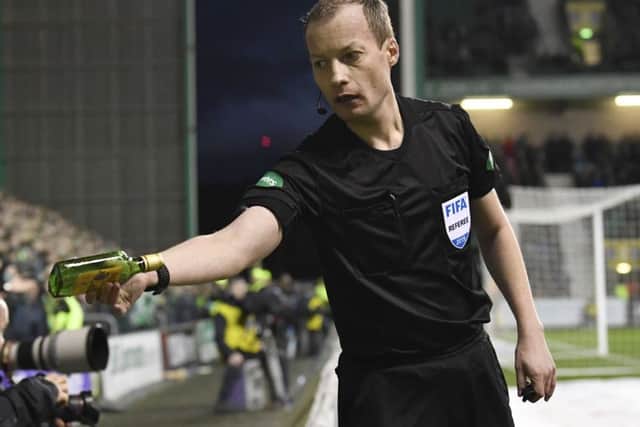 Referee Willie Collum removes a bottle thrown at Celtic winger Scott Sinclair