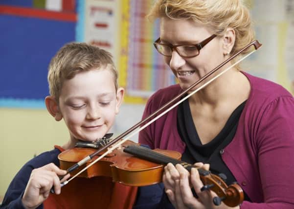 A teacher helps a pupil play the violin.