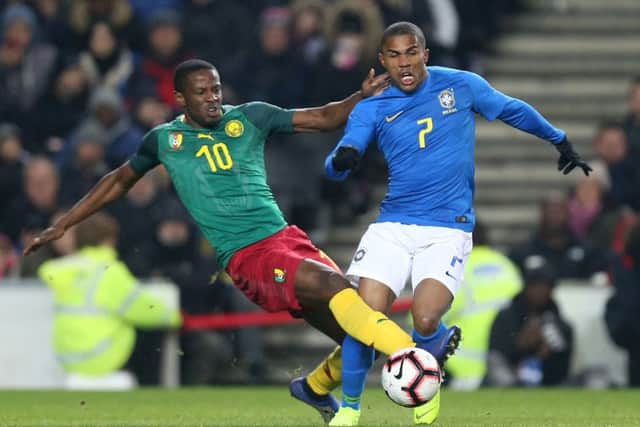 Arnaud Djoum challenges Douglas Costa of Brazil during a friendly last November in Milton Keynes