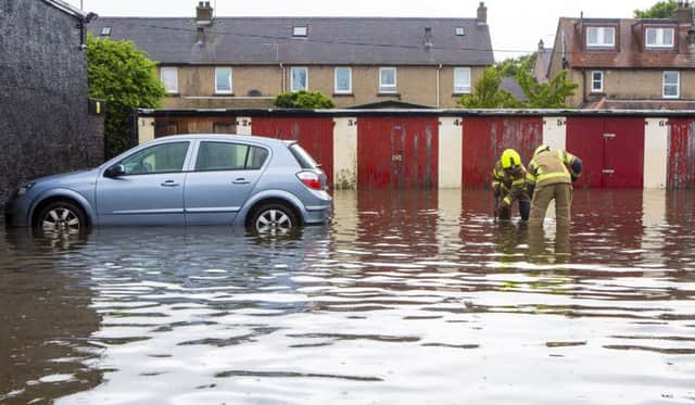 Fire brigade officers look for a blocked drain which has flooded a car park, leaving one car flooded in Barnton, Edinburgh.